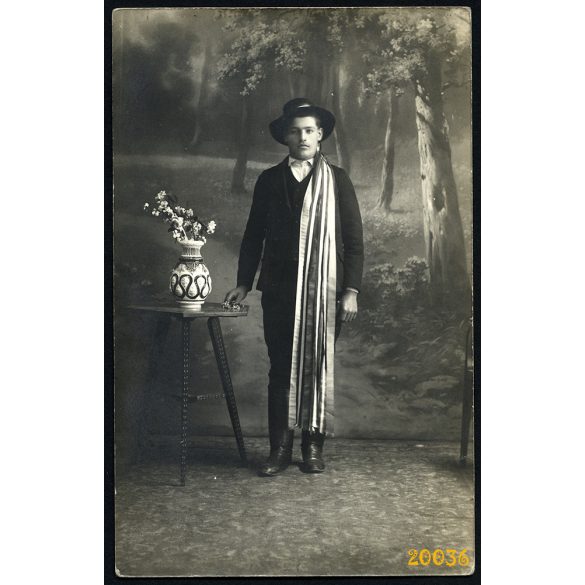 Fiú népviseletben, kalapban csizmában, szalaggal, különös háttér, Magyarország, 1920-as évek, Eredeti fotó, papírkép.  