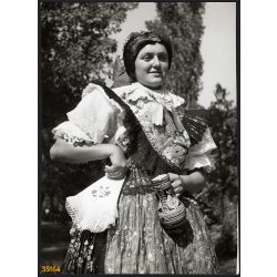   Nagyobb méret, Szendrő István fotóművészeti alkotása. Fiatal nő hosszúhetényi népviseletben, Hosszúhetény, Baranya megye, keszkenő, korsó, Gyöngyösbokréta mozgalom, néprajz, helytörténet 1930-as évek.