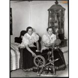 Nagyobb méret, Szendrő István fotóművészeti alkotása. Fiatal asszonyok, rokkával, cserépkályha, Kustánszeg, Zala megye, 1930-as évek. Eredeti, pecséttel jelzett fotó, papírkép, Agfa Brovira papíron. D