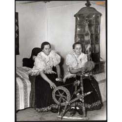   Nagyobb méret, Szendrő István fotóművészeti alkotása. Fiatal asszonyok, rokkával, cserépkályha, Kustánszeg, Zala megye, 1930-as évek. Eredeti, pecséttel jelzett fotó, papírkép, Agfa Brovira papíron. D