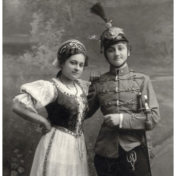 Fiatal pár műteremben, magyaros viselet, huszár (?) egyenruha, kard, 1. világháború, 1916, 1910-es évek, Eredeti fotó, papírkép.   