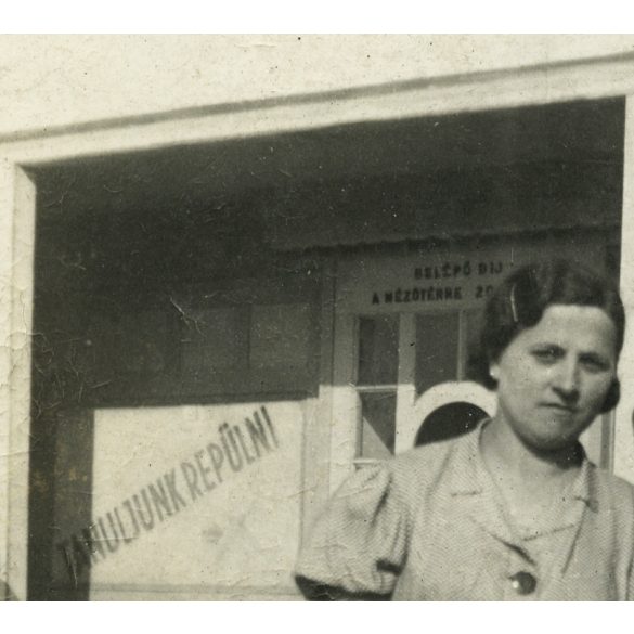 Elegáns pár egy épület előtt, „Tanuljunk repülni” felirat repülőgép rajzával, jármű, közlekedés, Horthy-korszak, 1936. 1930-as évek, Eredeti fotó, papírkép. 