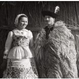 Nagyobb méret, Szendrő István fotóművészeti alkotása, fiatal pár kalocsai népviseletben, Gyöngyösbokréta mozgalom, Kalocsa, Bács-Kiskun megye, népviselet, suba, szoknya, kalap, kunyhó, 1930-as évek. 