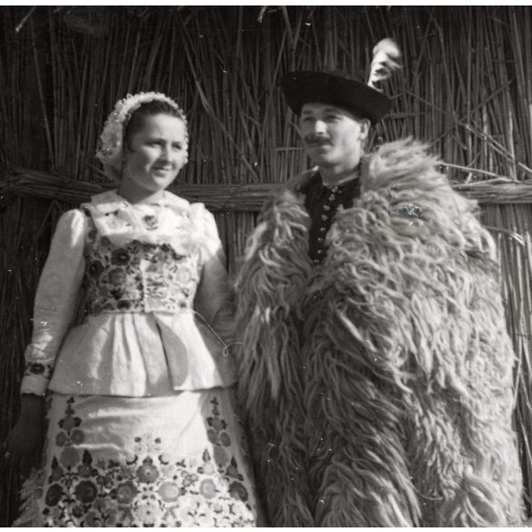 Nagyobb méret, Szendrő István fotóművészeti alkotása, fiatal pár kalocsai népviseletben, Gyöngyösbokréta mozgalom, Kalocsa, Bács-Kiskun megye, népviselet, suba, szoknya, kalap, kunyhó, 1930-as évek. 